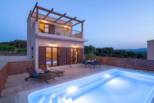 a villa with a swimming pool in front of a house at Luxury Villa Malvasia with Seaview and Heated pool in Epáno Váthia