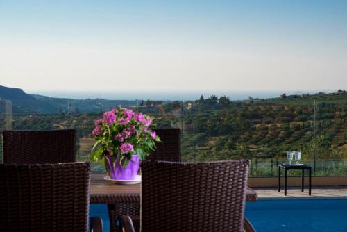 a table and chairs with a vase of flowers on it at Luxury Villa Malvasia with Seaview and Heated pool in Epáno Váthia