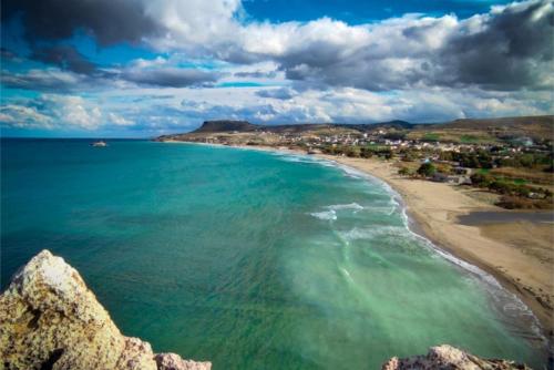 a view of a beach with a town in the distance at Luxury Villa Malvasia with Seaview and Heated pool in Epáno Váthia