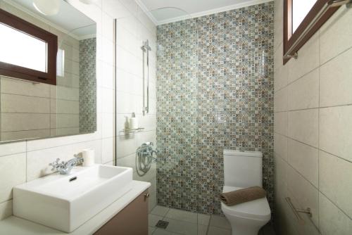 a white bathroom with a sink and a toilet at Luxury Villa Malvasia with Seaview and Heated pool in Epáno Váthia