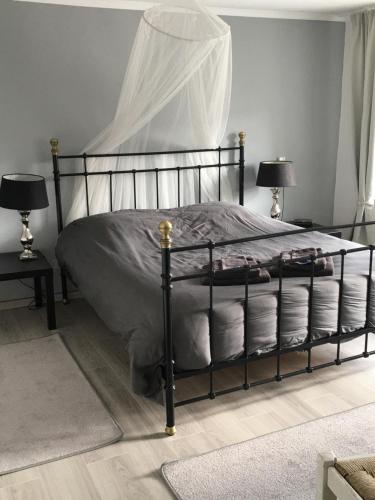 a bedroom with a black bed with pillows and two lamps at Eifel-Moezelhuis in Bergweiler