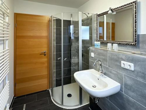 La salle de bains est pourvue d'un lavabo et d'une douche. dans l'établissement Ferienwohnung *Haus Ose*, à Wittdün