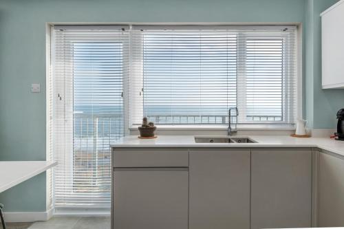 cocina con armarios blancos y ventana grande en Dolphins Apartment - Spectacular Sea Views, en Saundersfoot