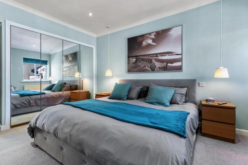 - une chambre avec un grand lit aux murs bleus dans l'établissement Dolphins Apartment - Spectacular Sea Views, à Saundersfoot