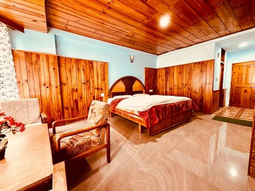 a bedroom with a bed and a wooden wall at Hotel D Kanchan Manali in Manāli