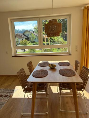 a dining room table with chairs and a large window at Ferienwohnungen Rössle in Stiefenhofen