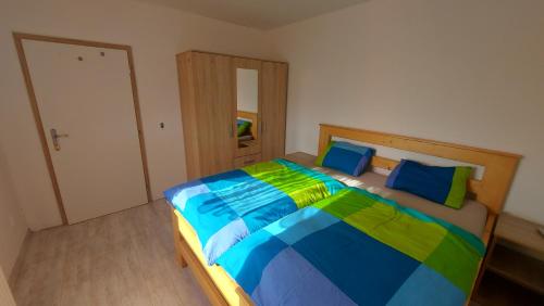 ein Schlafzimmer mit einem farbenfrohen Bett mit blauen und grünen Kissen in der Unterkunft Apartmán Rudoltice 