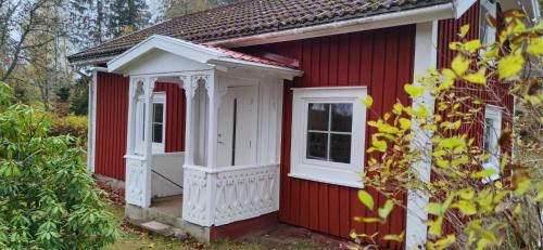 Casa roja y blanca con puerta y ventanas blancas en Stuga Koppekull Långasjö, en Långasjö