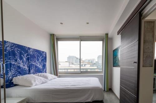 - une chambre avec un lit doté d'une tête de lit bleue et d'une fenêtre dans l'établissement Le Suffren-Eiffel Appartement, à Paris