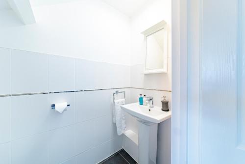 a white bathroom with a sink and a mirror at Greyfriars in Clacton-on-Sea
