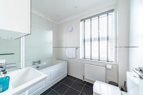 a white bathroom with a tub and a sink at Greyfriars in Clacton-on-Sea