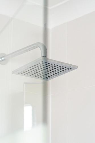 a metal shower head in a white bathroom at Greyfriars in Clacton-on-Sea
