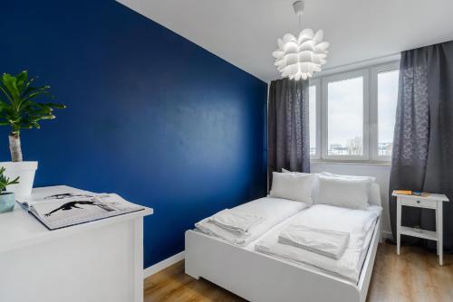 - une chambre bleue avec un lit blanc et un mur bleu dans l'établissement ShortStayPoland Grochowska (B112), à Varsovie