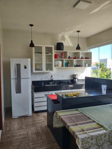 a kitchen with a white refrigerator and a sink at Xodó da Praia - amplo apartamento 3 qts 260 m da praia in Santa Cruz