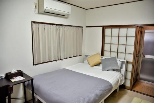 a small bedroom with a white bed and a window at Osaka U-Shuku in Osaka