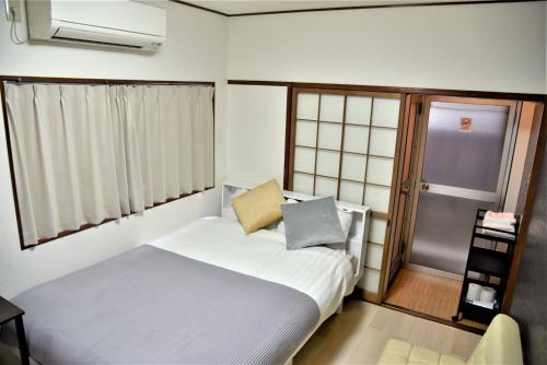 a small bedroom with a white bed and a window at Osaka U-Shuku in Osaka