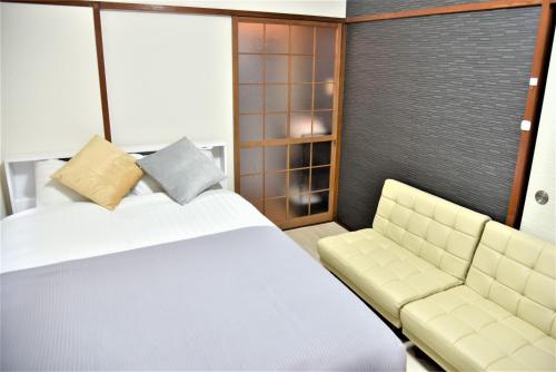 a bedroom with a bed and a couch at Osaka U-Shuku in Osaka