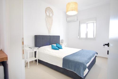 a white bedroom with a bed with blue pillows at Asteria Apartments in Analipsi