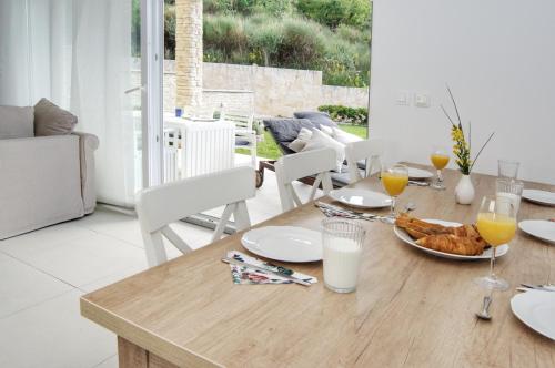 a wooden table with a plate of food and glasses of orange juice at Ferienhaus mit Meerblick & Pool in Baška - Villa-Planina in Baška