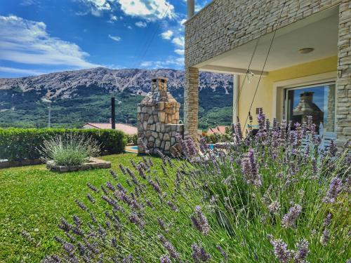 a house with a garden with purple flowers at Ferienhaus mit Meerblick & Pool in Baška - Villa-Planina in Baška