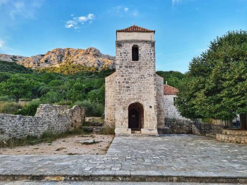 an old stone building with a bell tower at Ferienhaus mit Meerblick & Pool in Baška - Villa-Planina in Baška
