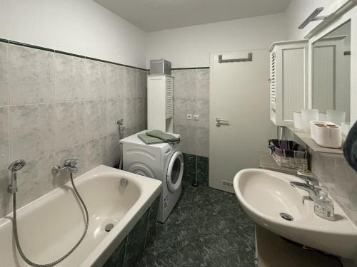 een badkamer met een bad, een wastafel en een wasmachine bij Ferienwohnung Arlett in Dresden