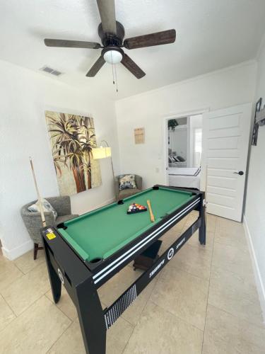 a pool table in a living room with a ceiling fan at Crest Lake Beach House in Clearwater