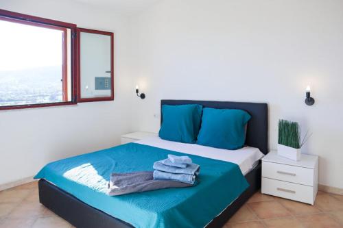 een slaapkamer met een bed met blauwe lakens en een raam bij Budoni Villetta Arno P1 in Budoni