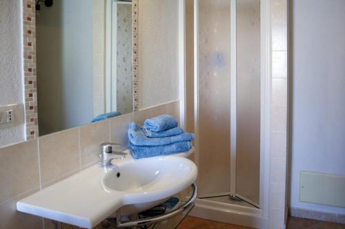 een badkamer met een wastafel en een douche met handdoeken bij Budoni Villetta Arno P1 in Budoni