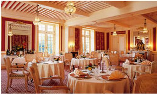 uma sala de jantar com mesas e cadeiras com toalha de mesa branca em Château de Rigny em Gray