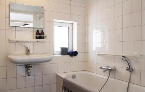 a white tiled bathroom with a sink and a tub at Houtsnip in Ommen