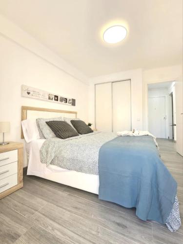 a white bedroom with a large bed and a wooden floor at Mavi Torre del Mar in Torre del Mar
