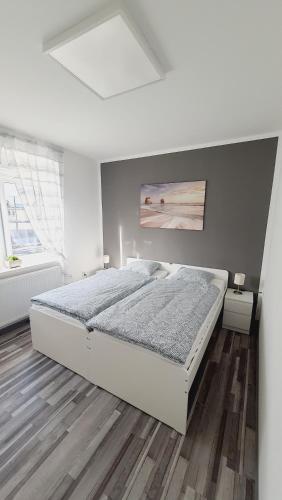 a white bedroom with a bed and a wooden floor at Apartma4us in Maribor