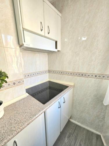 a kitchen with white cabinets and a sink at Mavi Torre del Mar in Torre del Mar