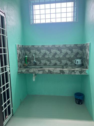 een blauwe badkamer met een wastafel en een raam bij RUMAH CHANGGONG Studio in Kota Bharu