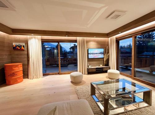 uma sala de estar com uma mesa de vidro e uma televisão em Les Chamois D’Arbois, Mont D’Arbois, Megève em Megève
