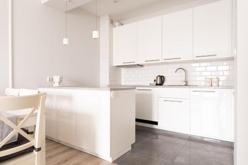 una cocina blanca con armarios blancos y fregadero en Apartament Symfonia Mozarta, en Warka