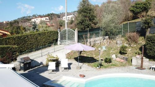 a pool with an umbrella and chairs and a grill at La casa nel verde con piscina in Polverara