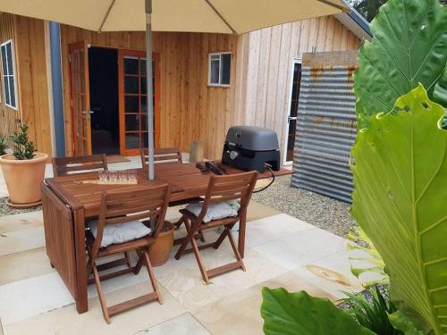 drewniany stół i krzesła z parasolem na patio w obiekcie Riverstay on Clarence w mieście Seelands