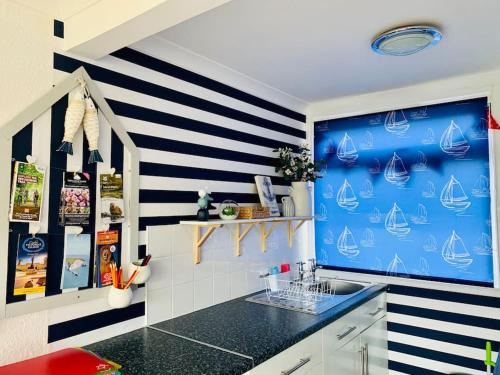 a kitchen with a blue and white striped wall at “BLISS ON THE BAY ” chalet in Sandown Bay Holiday Park in Sandown