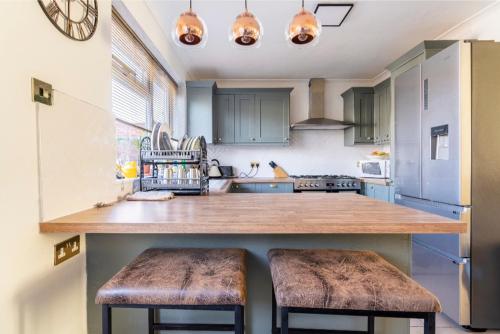 una cocina con un gran mostrador de madera con 2 taburetes en Lovely house (Ealing, London) en Londres