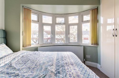 sypialnia z łóżkiem i dużym oknem w obiekcie Lovely house (Ealing, London) w Londynie