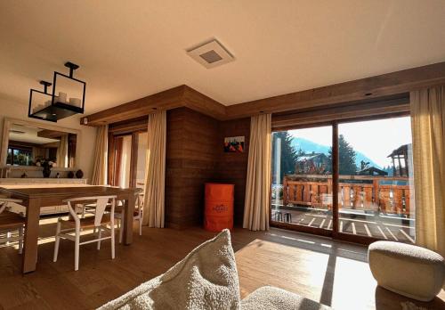 a living room with a dining room table and a large window at Les Chamois D’Arbois, Mont D’Arbois, Megève in Megève