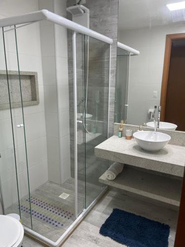 a bathroom with a glass shower and a sink at Itacimirim Beira Mar in Itacimirim