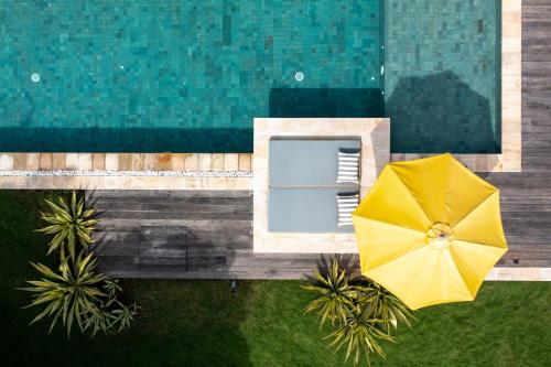 einen Blick über einen Pool mit gelbem Regenschirm in der Unterkunft Katoni Villa Lembongan in Nusa Lembongan