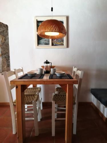 a wooden table with white chairs and a light at The Yellow Boat House in Klima