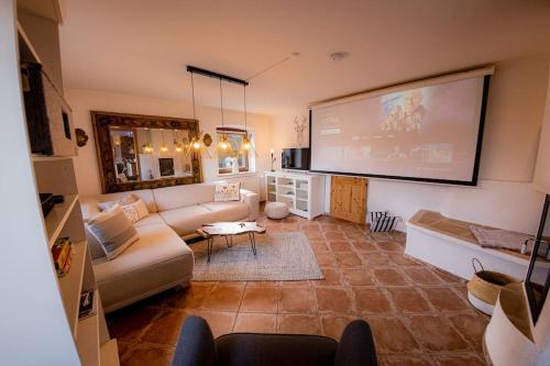 uma sala de estar com um sofá e um grande ecrã em Gemütliche Wohnung mit Sauna Garten und Heimkino em Anger