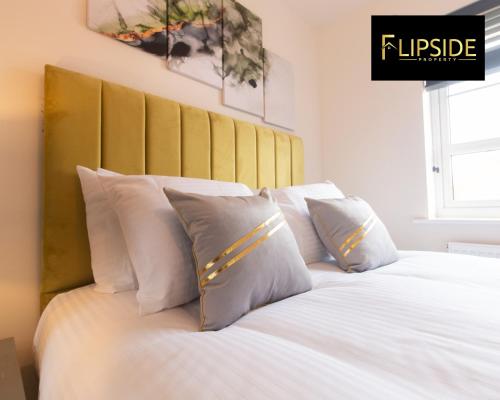 1 cama con almohadas blancas y cabecero amarillo en Contractors & Groups & Family Relocation - Flipside Property Aylesbury - Call Us Today For Special Offer!, en Bierton