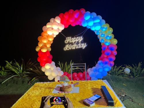 Heavens Edge Resort في ماهاباليشوار: طاولة مع علامة عيد ميلاد سعيد والبالونات