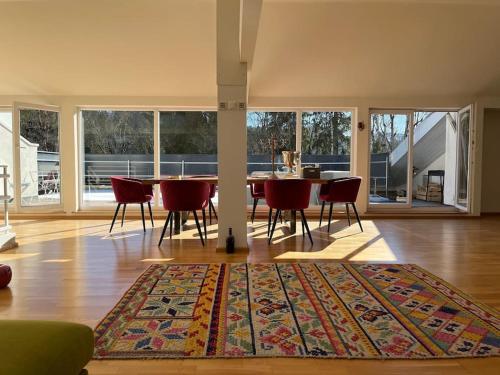a dining room with a table and chairs and a rug at Sonnige Loft mit Terrasse, Ladestation für Elektrofahrzeuge in Schindellegi